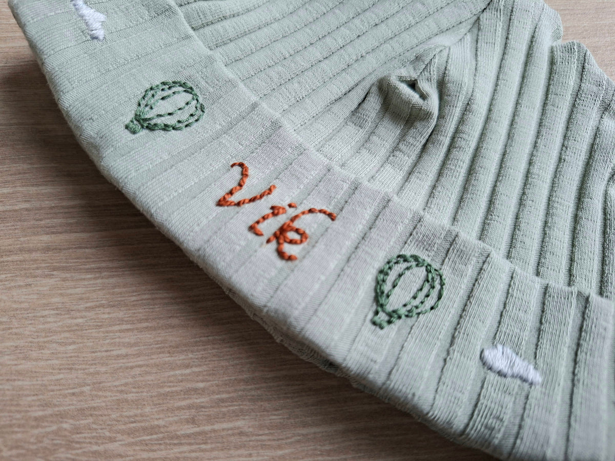 Handgeborduurd babymutsje met naam en decoratie
