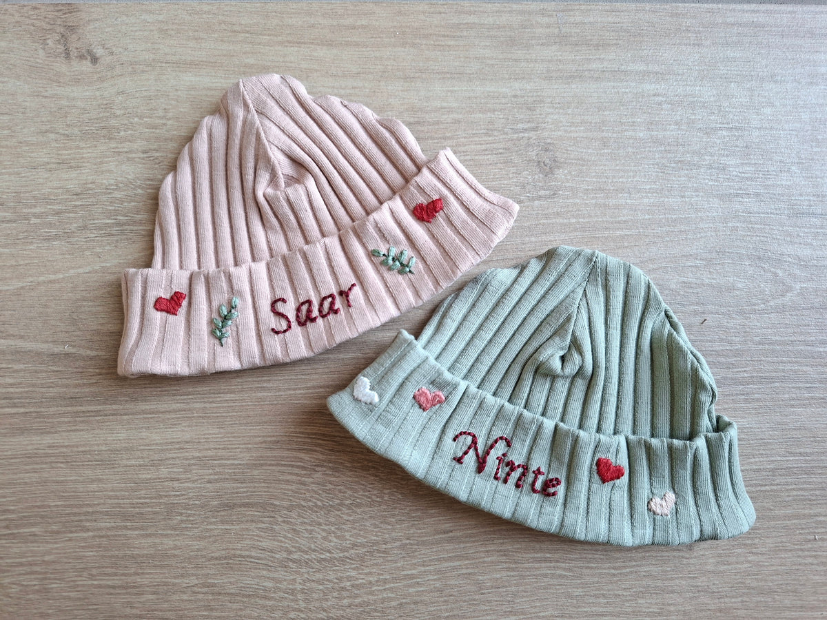 Handgeborduurd babymutsje met naam en decoratie